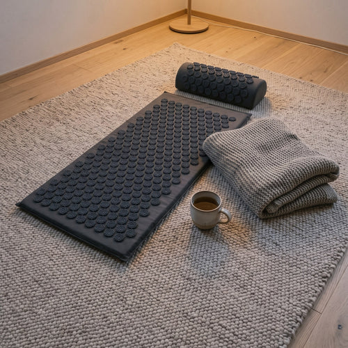 Acupressure mat and pillow on a wool rug with tea at dusk