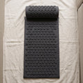 Dark gray acupressure mat and neck pillow on ivory linen